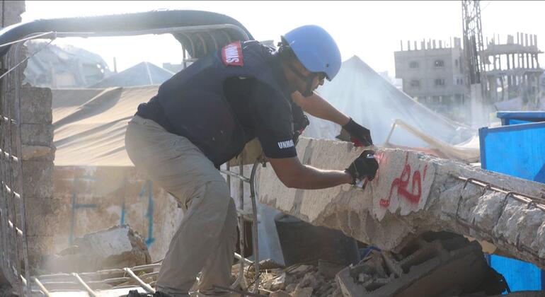 يقوم عضو في فريق دائرة الأمم المتحدة للإجراءات المتعلقة بالألغام (أونماس) بتحديد موقع لمخلفات الحرب المتفجرة بين المباني المدمرة.